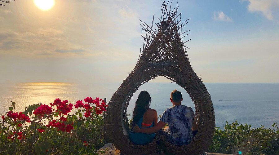Couple enjoying sunset on Uluwatu cliff.