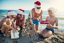 Families enjoying beach activities with Christmas decorations around.