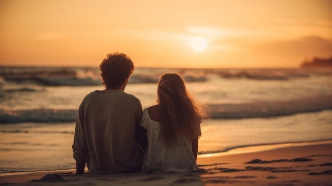 View of a couple sitting facing the sunset on a Bali beach